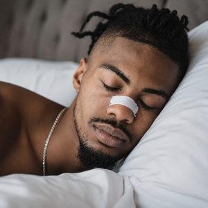 Person applying a nasal strip before bed as part of a nighttime sleep routine
